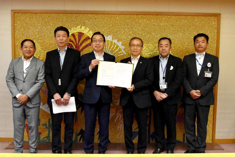 協定書を持つ松戸市長（右から３人目）と赤田社長（同４人目）＝船橋市
