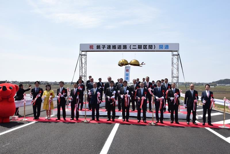 銚子連絡道路の新たな開通区間でテープカットとくす玉開きを行う関係者ら＝３月３１日、匝瑳市
