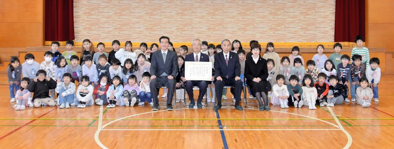 ３小中学校に滑り台などを寄贈した飯沼会長（中央左）と、感謝状を手渡した小坂町長（同右）ら＝１９日、酒々井小