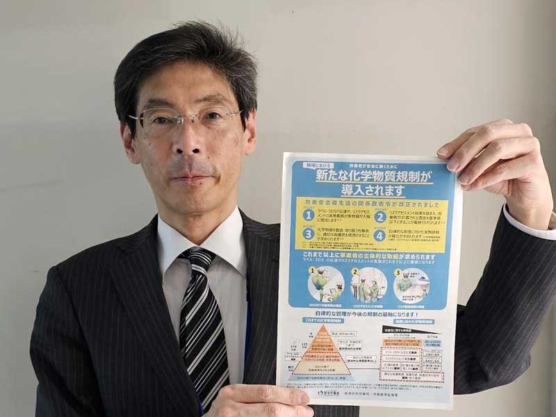 化学物質の新規制が導入されたことを伝えるパンフレットを手にする県労働局の関副主任＝４日、千葉市中央区の千葉労働局
