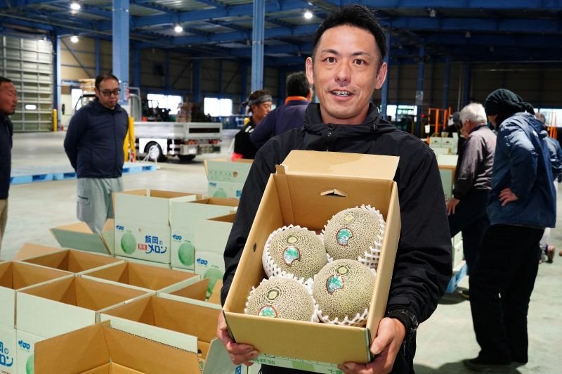 出荷されるメロンを手にする飯岡メロン部会の向後会長＝３０日、旭市