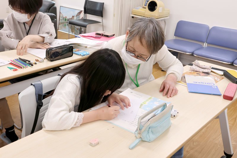 ＮＰＯのスタッフから日本語を教わる子ども＝４月、松戸市