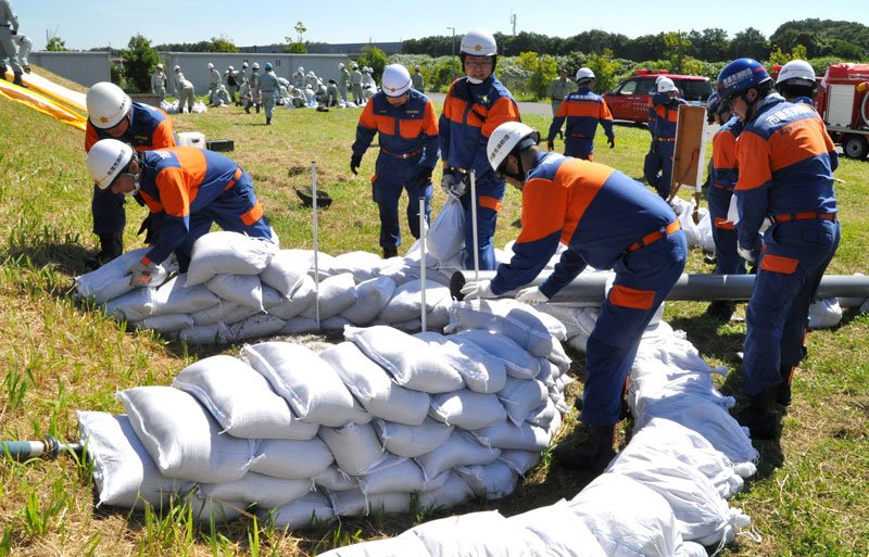 猛暑の中、堤防の漏水箇所に土のうを積む消防団員＝２２日、市原市菊間の県消防学校