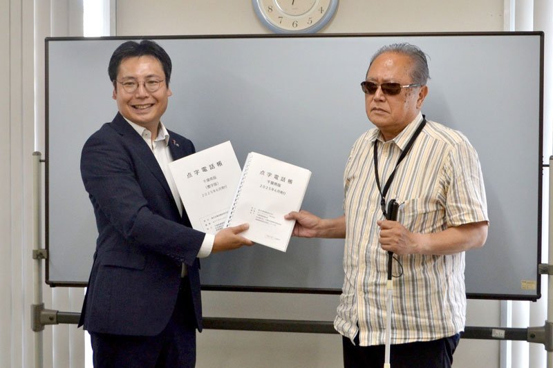 今野会長（右）に点字電話帳を手渡す井上事業部長＝四街道市の県視覚障害者福祉協会