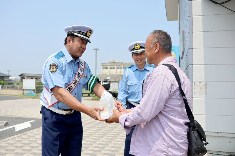 一日署長として交通安全啓発グッズを手渡す永田選手（左）＝９日、九十九里町の海の駅九十九里