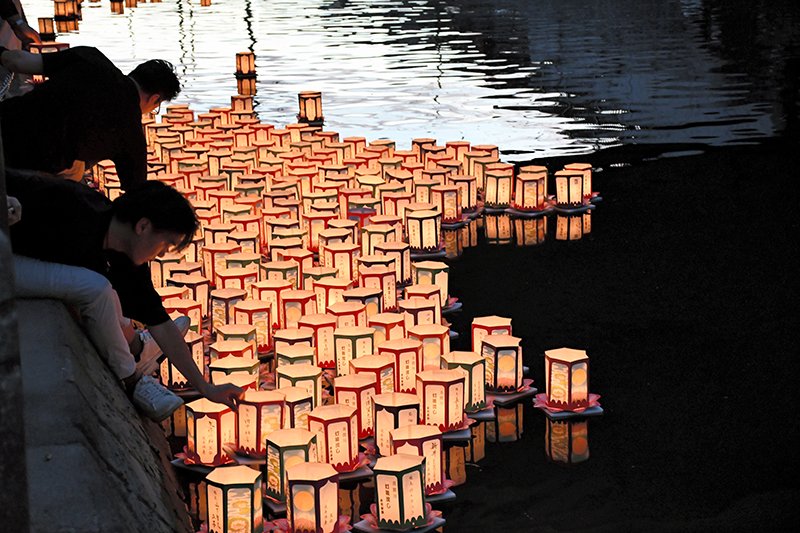 次々と真間川に流される灯籠＝１９日夜、市川市