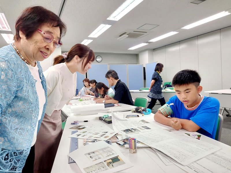千葉空襲を体験した高山さん（左）に取材しながら新聞を制作する子どもたち＝千葉市中央区