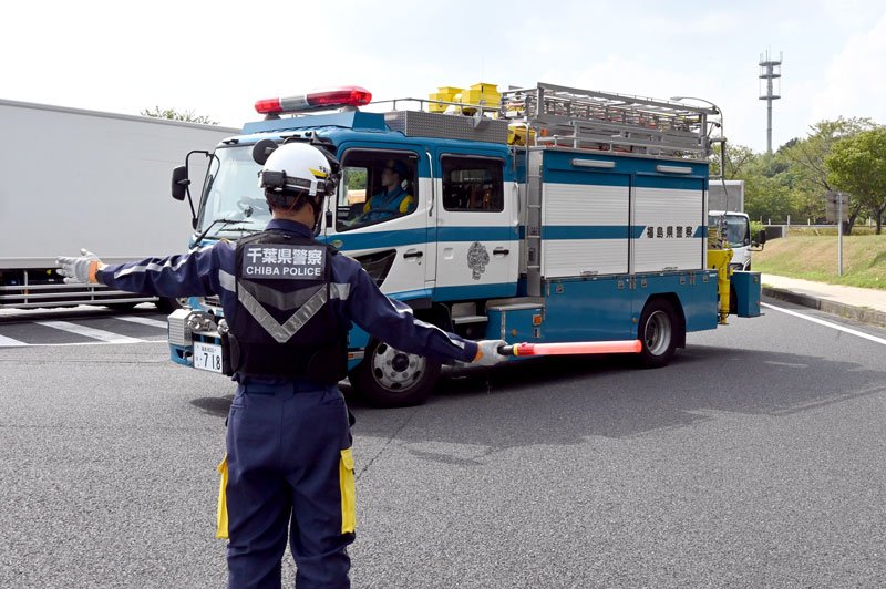 福島県警の車を誘導する千葉県警の警察官＝２５日、茨城県守谷市の常磐自動車道守谷サービスエリア
