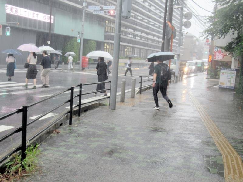 激しい雨が降り出し、足元に注意しながら急ぐ人たち＝５日午後１時前、市川市
