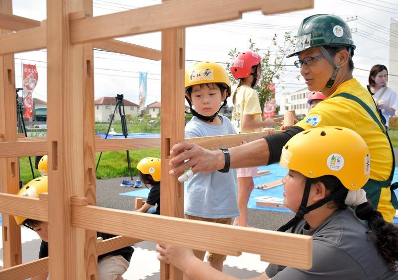 木育コーディネーターの竹内さんに習って木製のジャングルジムを組み立てる子どもたち＝富里市
