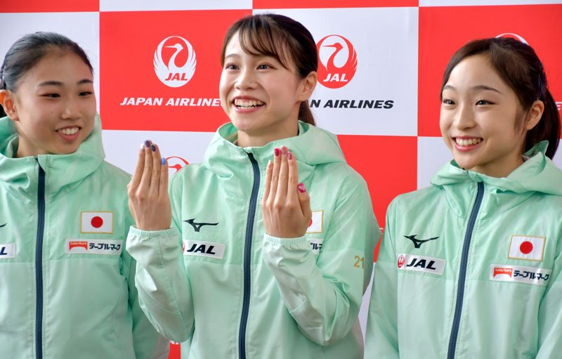 メダル獲得の願をかけて王冠を描いたネイルを披露する杉原選手（中央）＝１４日、成田空港