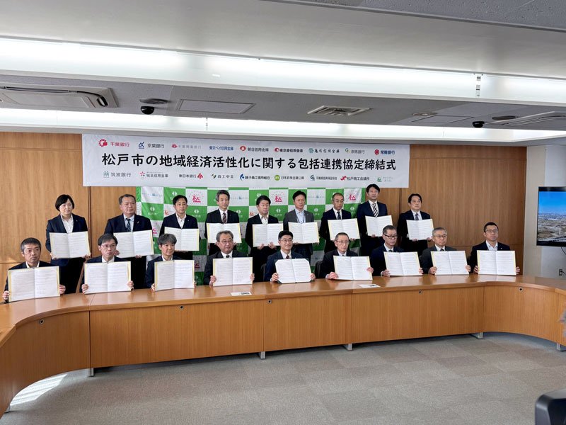 包括連携協定締結式で、各機関の代表者と共に協定書を掲げる松戸市長（中央）＝松戸市役所