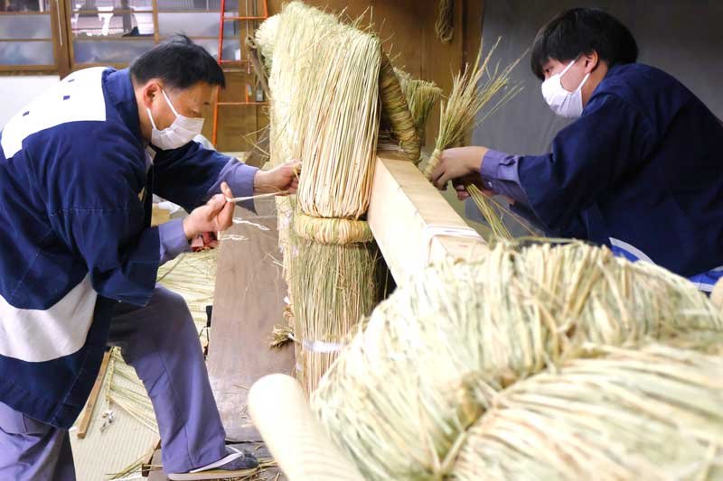 成田山新勝寺で、正月の大本堂前に飾られる大しめ縄作りが進められている。工務員が丁寧にわらを編み込み、形を整えていった＝１日、成田市