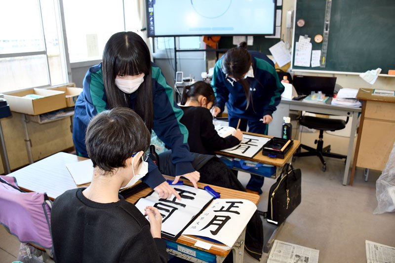 「書き初め」の練習で児童を指導する書道部員＝市川市