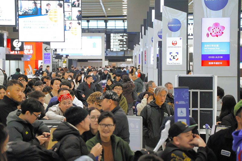 搭乗手続きのカウンターに長い列ができるなど旅客でにぎわう成田空港＝２６日、成田市