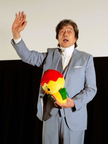 旭市のマスコット人形を持って来場者に手を振る中村さん＝１８日、旭市のサンモールシネマ