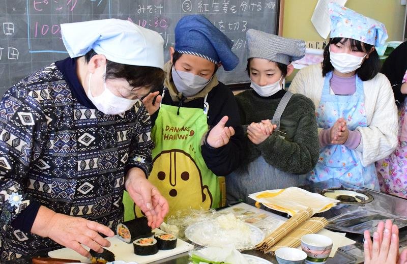 講師の大森さん（左）が作った鮮やかな花模様に「すごい」「きれい」と拍手する児童＝長南小


