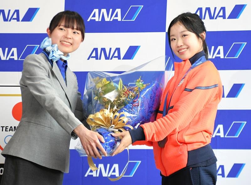 ミラノ・コルティナ冬季五輪のフィギュアスケート女子シングルで銅メダルに輝き、成田空港のスタッフから祝福の花束を手渡される中井選手（右）＝２４日午後、成田市の成田空港

