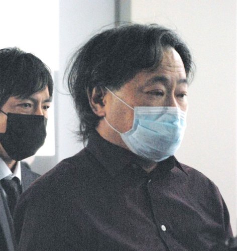 日本に到着した航空機を降り、捜査員に囲まれて歩く容疑者（右）＝４日午後６時５分ごろ、東京都大田区の羽田空港第２ターミナル
