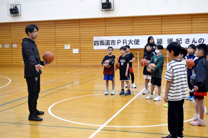 小学生にバスケの技術を教える佐藤さん（左）＝四街道市の四街道総合公園体育館