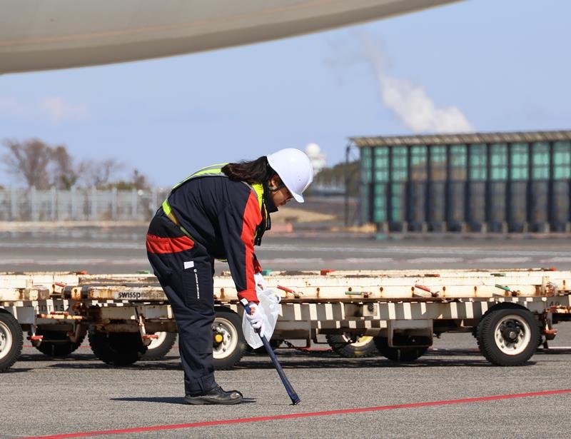 成田空港の駐機場でトングを使ってごみを拾うＪＧＳ社員＝１１日、成田市