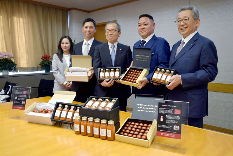 次世代農法で栽培された船橋産トマトを使ったジュースを松戸市長（中央）に披露するトマト生産者ら＝船橋市役所