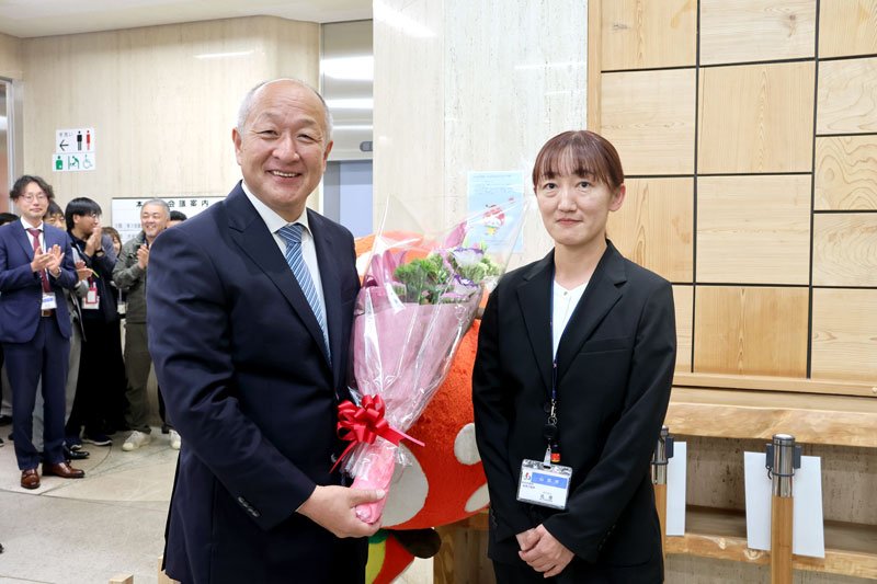 初登庁し花束を受け取った山武市の小野崎市長（左）＝２３日、市役所