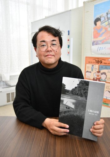 成田空港の機能強化に伴い全戸が移転対象となっている多古町一鍬田地区の写真集を紹介する斉藤さん＝多古町
