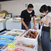 鮮魚店で客に魚のさばき方や食べ方を説明する森田釣竿さん（左）＝７月、浦安市(共同)