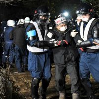 機動隊員に両脇を抱えられ農地から排除される市東さんの支援者＝１５日午後９時３６分、成田市天神峰