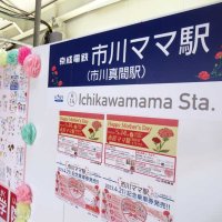 市川真間駅の構内に登場した「市川ママ駅」の看板。奥は子どもたちが描いた家族の絵＝市川市