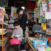 ずらりと並ぶ駄菓子からお気に入りを選び、かごに入れる子どもたち