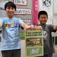 布鎌小の創立１５０周年の記念グッズを手に持つ児童
