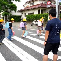 警察官（奥）や教員に見守られながら横断歩道を渡る御宿小児童