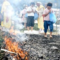 熱さの残る灰の上を歩き火渡り修行をする参拝客ら
