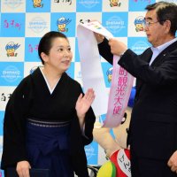石井和芳町長から観光大使のたすきを掛けられる三遊亭律歌さん（左）＝４日、白子町役場