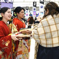 華やかな着物姿で成田空港の国際線利用客に日本酒を配るＪＡＬスタッフ＝１日、成田市