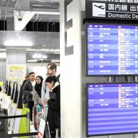 日本各地と結ぶ国内線を案内する電光掲示板（右）と、新千歳行き便への搭乗でチェックインカウンターに並ぶ旅客たち＝１０日、成田市の成田空港ＬＣＣターミナル