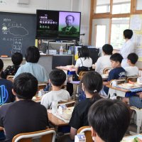 記念給食に合わせ、旭と渋沢の交流を紹介する動画を見る児童ら