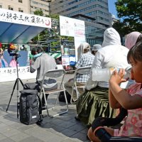 強い日差しが照り付ける「千葉の親子三代夏祭り」のダンスステージ会場で、凍らせたペットボトルのドリンクを口にする女児＝１７日午後、千葉市中央区の中央公園
