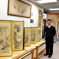 佐原の絵師、坂本桃渕の没後１００年の節目に開かれている作品展で、作品を紹介する親族の坂本興久さん＝香取市