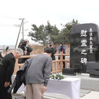 慰霊碑の前で犠牲者の冥福を祈る人たち＝１１日、旭市