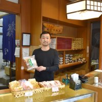 商品を手に今後の事業展開を話す長島淳一専務

