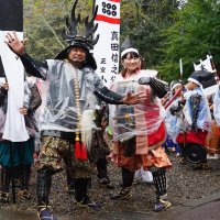 「出陣」を前に、撮影に応じる本多忠勝役の渡辺正行さん（左）と、軍奉行役のものまね芸人・沙羅さん。多くの参加者がビニールで雨よけをして歩いた＝大多喜町