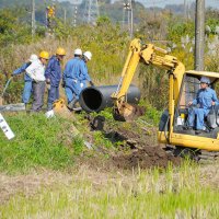 小湊鉄道線路脇ののり面崩落現場で、復旧に向け、埋設されていた用水管の入れ替えを行う作業員＝７日午前１０時ごろ、市原市磯ケ谷