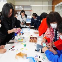 法被を着た町商工会女性部メンバーに教わりながらつるし雛の飾りを作る中学生ら＝御宿町
