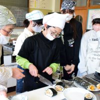 ボランティア（左）と共に太巻きずしを作る児童＝長南小