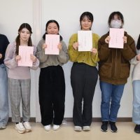 調査合宿の成果をまとめた中間報告書を持つ学生