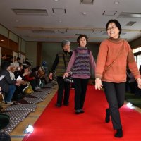 笑顔でレッドカーペットが敷かれたランウェイを歩く参加者