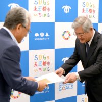 小出市長（手前）に構想を手渡す田中会長
